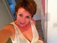 Woman with short dark hair in a white top, taking a selfie from above